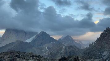 Timelapse of Landscape Cliffs and Peaks in Fann Mountains at Dusk, shrouded in ominous Gloomy Clouds. Bright Sky and rocky terrain create a powerful contrast, nature , travel, untouched wildlife. video