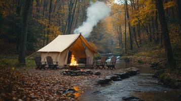 Smoke rising from campfire in front of tent near river in autumn forest photo
