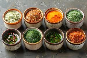 Assorted Dried Herbs and Spices in Ceramic Bowls on a Rustic Stone Surface for Culinary Use photo