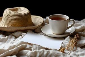 Rustic Breakfast Setting with Tea, Straw Hat, and Blank Note on White Fabric Cozy and Inviting Atmosphere photo