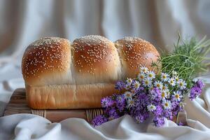 Rustic Loaf of Bread with Sesame Seeds and Fresh Wildflowers on a Wooden Surface Ideal for Culinary and Bakery Themes photo