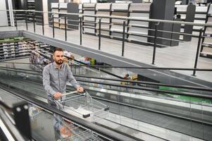 A man with a shopping cart on an escalator in a hardware store. photo