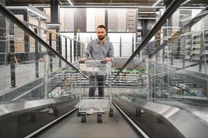 A man with a shopping cart on an escalator in a hardware store. photo