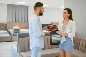 Focus on samples of colored fabrics for upholstered furniture. Overhead view of couple choosing color and fabric texture for upholstery sofa in the home. Interior design concept. photo