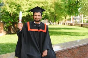 Handsome indian graduate in graduation glow with diploma photo