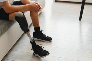 Closeup of unrecognizable man with bionic prosthetic leg at home indoors, copy space photo
