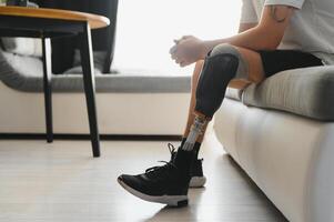 Closeup of unrecognizable man with bionic prosthetic leg at home indoors, copy space photo