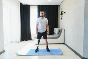 man exercising online stretching his legs at home, with amputated leg prosthesis photo