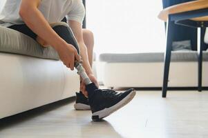 Closeup of unrecognizable man with bionic prosthetic leg at home indoors, copy space photo
