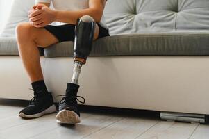Closeup of unrecognizable man with bionic prosthetic leg at home indoors, copy space photo
