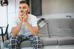 Man suffering from headache at home, touching his temples, copy space, blurred background. Migraine, headache, stress, tension problem, hangover concept photo
