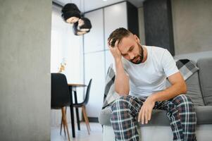 Man suffering from headache at home, touching his temples, copy space, blurred background. Migraine, headache, stress, tension problem, hangover concept photo