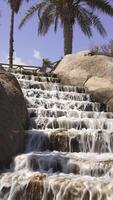 An artificial fountain descending down steps against a backdrop of palm trees video