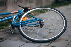 Blue bicycle with detached wheel on paved path, urban setting background photo
