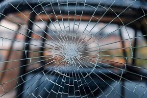 Shattered glass surface, spiderweb pattern, background reflections, varying damage intensity photo