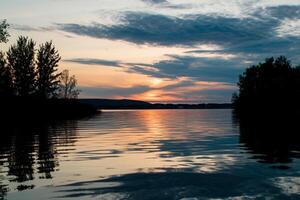 A lake with trees and water at sunset photo