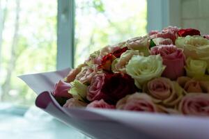 vibrant bouquet of multicolored roses set against the backdrop of a sun-drenched window, creating a serene and romantic scene photo
