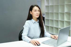 confident young woman spends her workday in a modern office, sitting at a desk and successfully completing tasks on a computer photo