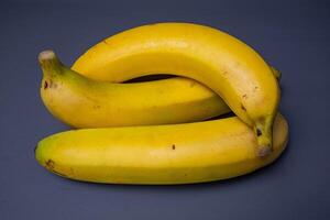 A banch of bananas and a sliced banana in a plate over brownd background. photo
