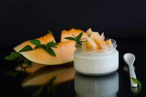 sweet homemade yogurt in a jar with pieces of ripe melon photo
