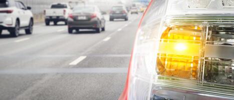 Vehicle left turn signal on a highway , close up of tail light of a car driving photo