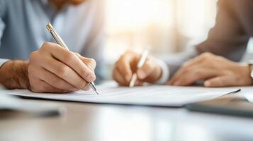 Close-up of two hands writing on a document, symbolizing teamwork and collaboration in a professional setting. photo