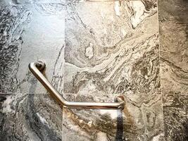 Stainless steel grab bar mounted on a marble bathroom wall, ideal for safety and accessibility in modern home design photo