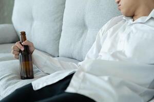 Depressed young business man addicted feeling bad drinking whiskey alone at home, stressed frustrated lonely drinking alcohol suffers from problematic liquor, alcoholism, life and family problems photo
