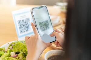Woman use smartphone to scan QR code to pay in cafe restaurant with a digital payment without cash. Choose menu and order accumulate discount. E wallet, technology, pay online, credit card, bank app. photo