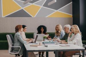 Group of confident mature women discussing business while having meeting in the office photo