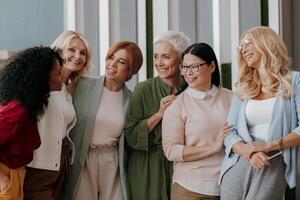 Group of happy mature women bonding and smiling while standing in the office together photo