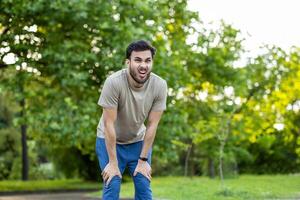 Young athlete pauses to catch breath after outdoor fitness session in vibrant green park. Expression of determination and challenge highlights physical endurance and mental resilience. photo