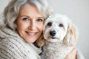 A joyful middle age woman with silver hair embraces her fluffy dog photo