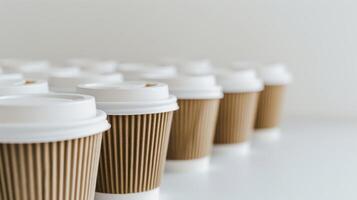 Row of disposable coffee cups with white lids on a clean white table photo