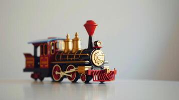 Small red and black toy train on a white surface with a plain white background photo