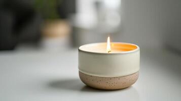 Modern pink and white candle is lit on a table, adding a warm glow to the space photo