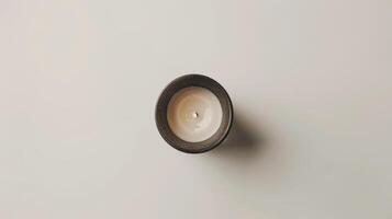 Single white soy candle burning in a dark gray container, providing a relaxing and cozy atmosphere photo