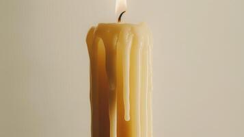 White candle is melting, forming fascinating patterns with its wax against a neutral backdrop photo