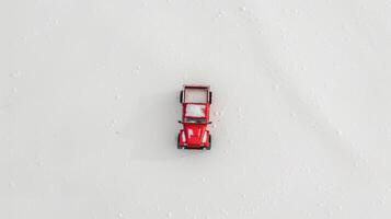 Red toy car sits on a snowy field, creating a festive winter scene photo