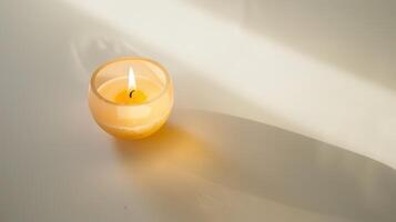 Round scented candle emits a warm glow, setting a cozy ambiance on a white table photo