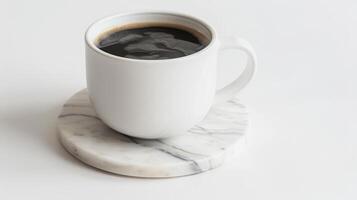 Hot cup of coffee is resting on a white marble coaster against a white backdrop photo