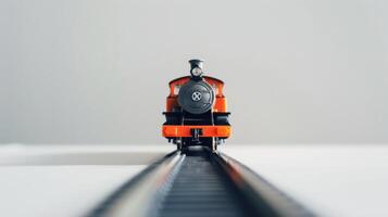 Orange toy train sits on model tracks, ready for a journey. photo