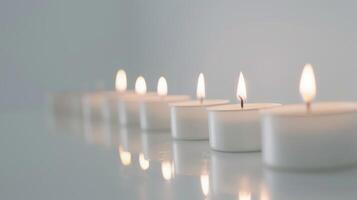 Line of white tea lights glowing on a shiny surface, evoking a calm and tranquil ambiance photo