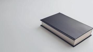 Black hardcover book rests on a white table, exuding simplicity and promise photo