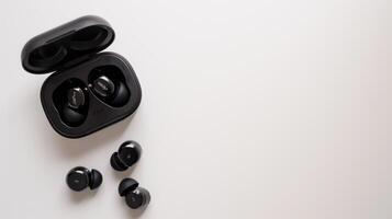 Wireless stereo earbuds and their charging case resting on a white table, ready for use photo