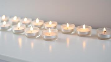 Row of softly glowing small candles on a white background creates a tranquil ambiance for relaxation and meditation photo