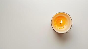 Single scented candle burning on a white table, creating a warm and inviting ambiance photo
