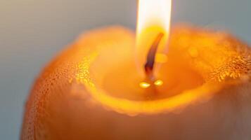 Close-up shot of a gentle candle flame casting a romantic and peaceful glow over melted wax photo