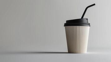 White paper coffee cup with black lid and straw on a gray background with space for text photo