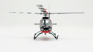 Toy helicopter in red and black stands on a white surface, its blades blurred by motion photo